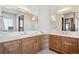 Double vanity bathroom featuring wooden cabinets, quartz countertops, and dual mirrors at 6194 Falcon Ridge Way, Morrison, CO 80465