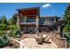 Multi-level back exterior featuring stone accents, covered balconies, and outdoor seating area with fireplace at 6194 Falcon Ridge Way, Morrison, CO 80465