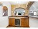 The wet bar features stone arch accents, cabinets, a wine cooler, and tile countertops at 6194 Falcon Ridge Way, Morrison, CO 80465