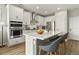 Bright kitchen featuring white cabinets, stainless steel appliances, and a center island with barstool seating at 7875 Yampa River Ave, Littleton, CO 80125