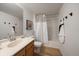 Well-lit bathroom features a single sink vanity, large mirror and combination shower and tub behind curtain at 8615 W Berry Ave # 204, Littleton, CO 80123