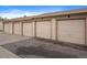 Multiple individual garages with concrete driveway and tan siding matching the tan doors and gutters at 8615 W Berry Ave # 204, Littleton, CO 80123