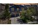 Two-story home with stone accents, blue siding, a two-car garage, and solar panels on the roof against a colorful sky at 25245 E Park Crescent Dr, Aurora, CO 80016