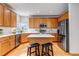 Well-lit kitchen featuring an island with seating, stainless steel appliances, and light wood cabinets at 25245 E Park Crescent Dr, Aurora, CO 80016