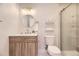 Elegant bathroom with wooden vanity, round mirror, and glass-enclosed shower at 1640 Iola St, Aurora, CO 80010