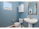 Comfortable powder room with pedestal sink, toilet, and blue painted walls at 427 S Parkside Dr, Longmont, CO 80501