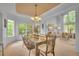 Formal dining room with tray ceiling, modern chandelier, and large windows providing ample natural light at 10356 Lions Heart, Lone Tree, CO 80124