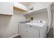 Bright laundry room features a white, front-load washer and dryer and convenient overhead storage at 14435 E 1St Dr # B2, Aurora, CO 80011