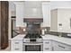 Well-appointed kitchen with stainless steel range, custom hood, white cabinets, and stylish backsplash at 10553 Stonemeadow Dr, Parker, CO 80134