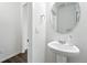 Elegant powder room featuring a pedestal sink, framed round mirror, designer fixtures, and vinyl flooring at 226 Racer St, Bennett, CO 80102