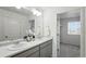 Double sink vanity in a bright bathroom with neutral decor, a large mirror, and access to a walk-in closet at 226 Racer St, Bennett, CO 80102