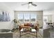 Bright living room with large windows, contemporary furnishings, ceiling fan and hardwood-style floors at 226 Racer St, Bennett, CO 80102