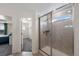 Modern bathroom featuring a glass-enclosed shower and neutral tile, and adjacent walk in closet and bedroom at 12826 Lake Port St, Longmont, CO 80504