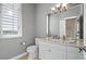 Bright, gray powder bathroom featuring a window with shutters, a chandelier, and a white vanity at 4505 W 100Th Ave, Westminster, CO 80031