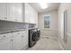 Well-lit laundry room featuring gray subway tile backsplash, front-loading washer and dryer, and white cabinetry at 4505 W 100Th Ave, Westminster, CO 80031