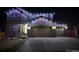 Nighttime view of a two-story home featuring a stone facade, multiple windows, and a two-car garage at 25064 E Archer Pl, Aurora, CO 80018