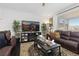 A living room has a brown leather couch, a dark wood floor, and a big window with sunlight at 25064 E Archer Pl, Aurora, CO 80018