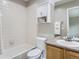 Cozy bathroom with white tiled walls, a built-in tub, and an oak vanity at 6827 S Webster St # E, Littleton, CO 80128