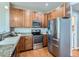 Modern kitchen with stainless steel appliances, granite countertops, and wood cabinets at 6827 S Webster St # E, Littleton, CO 80128