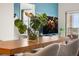 A dining table with place settings and a centerpiece with greenery in front of a TV and balcony doors at 1950 N Logan St # 905, Denver, CO 80203