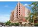 Upscale brick apartment building with balconies surrounded by lush green trees and a blue sky at 1950 N Logan St # 905, Denver, CO 80203
