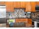 Well-equipped kitchen with granite counters, tile backsplash, stainless appliances, and natural wood cabinetry at 1950 N Logan St # 905, Denver, CO 80203