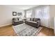 Living room with hardwood floors, natural light, grey sofa set, and a decorative rug at 13853 W 66Th Pl, Arvada, CO 80004