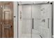 A shower is enclosed with glass, and the tile accents the door with dark wood grain and black hardware at 302 Northridge Rd, Highlands Ranch, CO 80126
