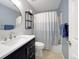 Stylish bathroom featuring modern vanity, open shelves, and a shower with a blue-and-white curtain at 2748 W Greens Dr, Littleton, CO 80123