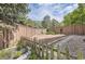View of backyard with fencing, garden beds, mature trees, rock ground cover and stepping stones at 9001 W Chatfield Dr, Littleton, CO 80128