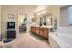 Bathroom featuring double vanity, large mirror, soaking tub, and access to the primary bedroom at 9001 W Chatfield Dr, Littleton, CO 80128
