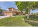 Beautiful front yard with a large shade tree, green lawn, and a two-story home featuring a three car garage at 9001 W Chatfield Dr, Littleton, CO 80128