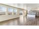 Open-concept living area featuring wood-look floors, large windows, and a modern kitchen in the background at 2231 Crosswind St, Fort Lupton, CO 80621