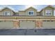 Attached garages with neutral-colored doors and brick accents on a row of townhomes at 1817 S Buchanan Cir, Aurora, CO 80018