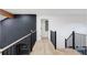 Modern hallway with wood floors, black brick accent wall, and black metal railings and banisters at 1 Winged Foot Way, Littleton, CO 80123