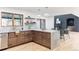 Open kitchen showcasing wood cabinets, marble countertops, an island with seating, and views of the living space at 1 Winged Foot Way, Littleton, CO 80123