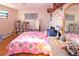 This bright bedroom features wood floors, natural light, a colorful quilt, and a decorative bookshelf at 1075 S Ames St, Lakewood, CO 80226