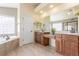 Bright bathroom featuring dual sinks, a large soaking tub with tile surround, and a glass-enclosed shower at 1122 Orion Way, Castle Rock, CO 80108