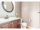 Neutral bathroom featuring a sink with wooden cabinets and granite countertop, plus toilet and modern round mirror at 1122 Orion Way, Castle Rock, CO 80108