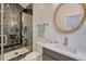 Elegant bathroom with marble shower, gold fixtures, and a round mirror above the sink at 520 Columbine St, Denver, CO 80206