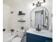 Bright bathroom features a blue vanity, tub and shower, and floating shelves at 6298 S Harlan Way, Littleton, CO 80123