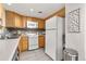 Kitchen with wood cabinets, neutral countertops, white appliances and modern backsplash at 970 S Dawson Way # 15, Aurora, CO 80012