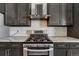 Close-up of updated kitchen with gas range, gray cabinets, stainless vent hood, and subway tile backsplash at 5238 Clearbrooke Ct, Castle Rock, CO 80104