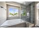 This bathroom features a tub, a glass-enclosed shower, and a bright window providing lots of natural light at 20455 E Grand Ln, Aurora, CO 80015