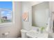 Bright half bathroom with a clean white sink, toilet, and modern fixtures and outside view at 9072 E 47Th Ave, Denver, CO 80238