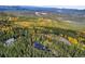 Aerial view of a mountain home surrounded by dense forest in vibrant fall colors at 10756 Timothys Dr, Conifer, CO 80433