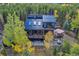 Breathtaking aerial view of a home nestled within a forest featuring decks and a black metal roof at 10756 Timothys Dr, Conifer, CO 80433