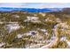 Panoramic aerial view showcases a home nestled among snow covered trees with mountain views at 10756 Timothys Dr, Conifer, CO 80433