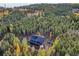 Aerial view of mountain home surrounded by evergreens and colorful fall foliage at 10756 Timothys Dr, Conifer, CO 80433