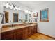 Elegant bathroom boasts dual sinks with granite countertops, and warm wood cabinetry at 10756 Timothys Dr, Conifer, CO 80433